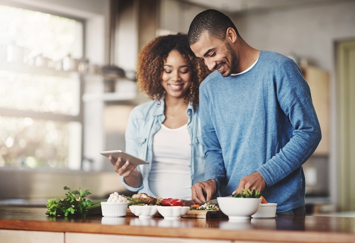 A couple making dinner with the food they bought from Dream Dinners Pasadena.